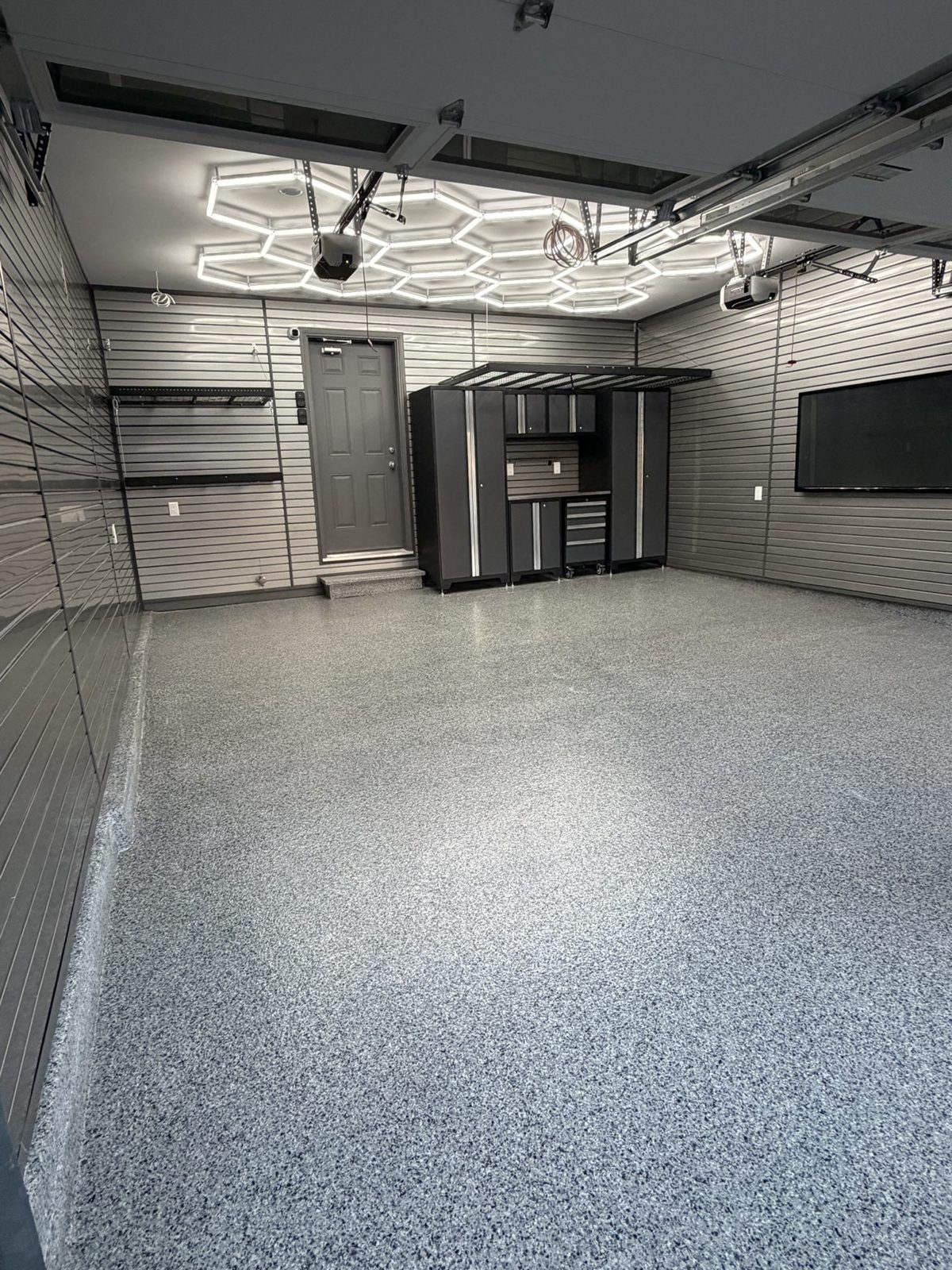 Garage after: flake epoxy floor, slatwall, cabinets and hexagon LED lighting